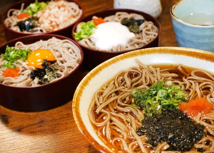 Bowl of Izumo Soba Noodles in the foreground, with various colorful toppings